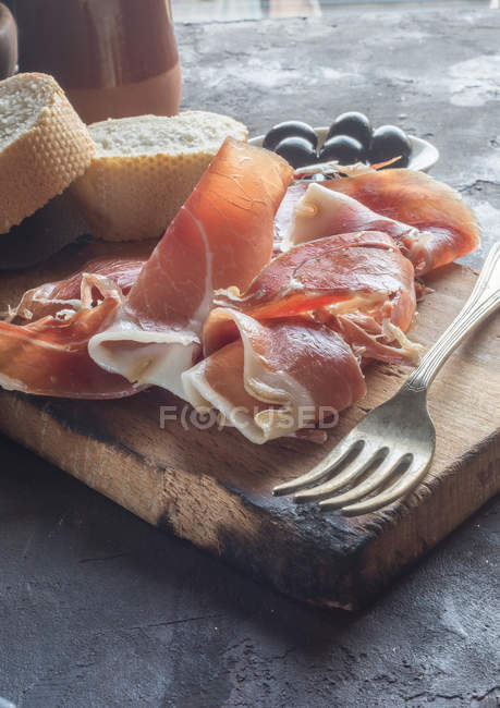 Cured ham with bread and olives — Stock Photo