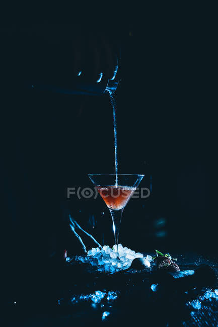 Коктейль бокал на кубики льда во время заливки — стоковое фото