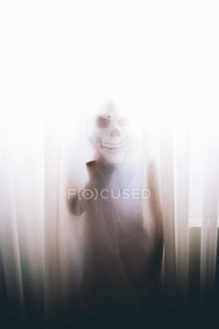 Silhouette Person mit Totenkopf-Maske hinter Vorhängen — Stockfoto