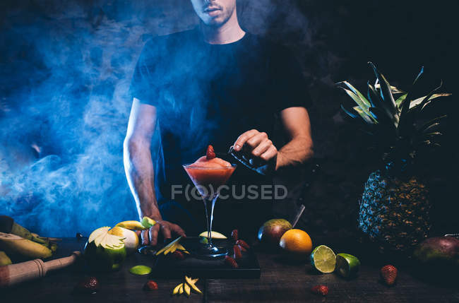 Man adjusting strawberry on cocktailglass — Stock Photo