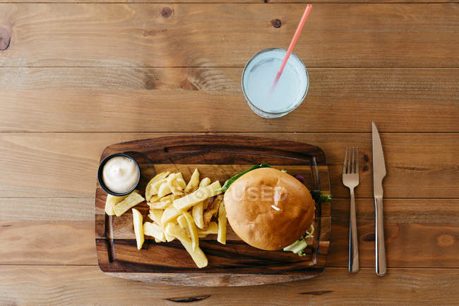 Burger and fries on wooden board. — Stock Photo