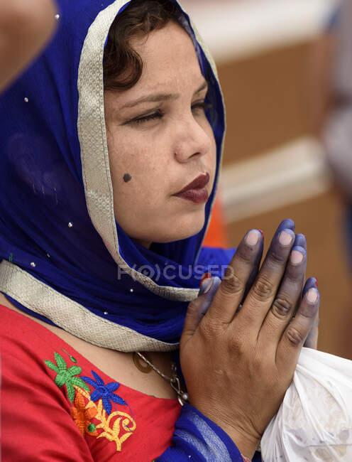 Young Indian woman in bright traditional clothes with praying hands. — Stock Photo