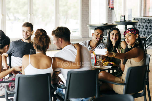 People posing and taking selfie while sitting with friends in restaurant. — Stock Photo
