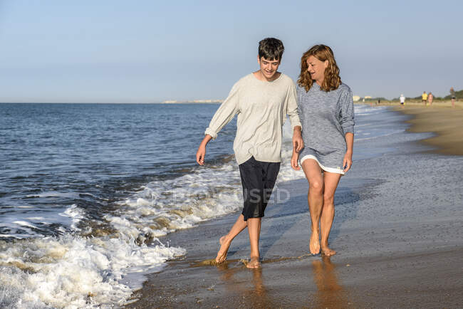 Madre e hijo divirtiéndose en la orilla de la playa - foto de stock