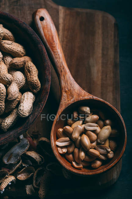 Vista de cerca de cacahuetes pelados en cucharada de madera a bordo - foto de stock