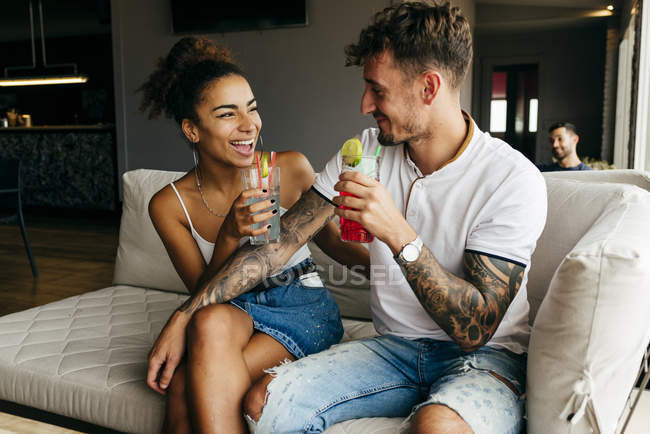 Couple heureux ayant des cocktails et assis sur le canapé — Photo de stock