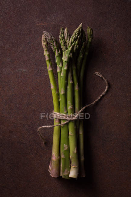 Bunch of green asparagus on dark metal background — Stock Photo