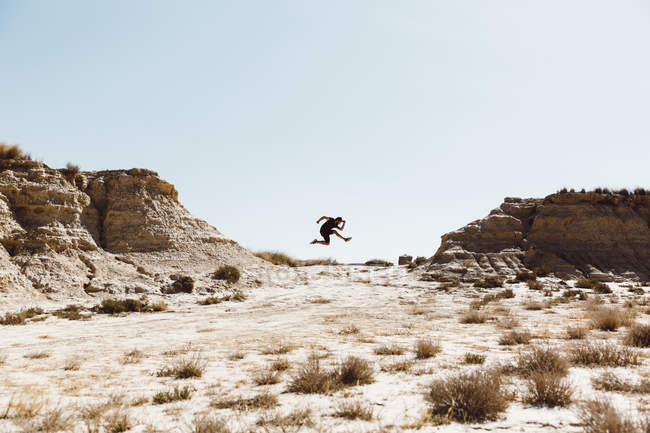 Seitenansicht eines Mannes, der beim Sprung in die Wüste posiert — Stockfoto