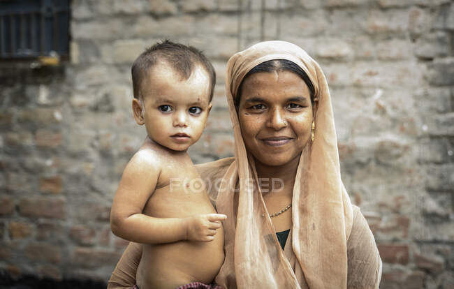 Smiling adult Indian mother with infant son looking at camera. — Stock Photo