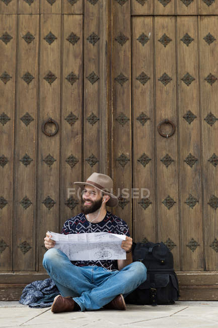 Touristin sitzt und liest Karte, während sie Musik hört — Stockfoto