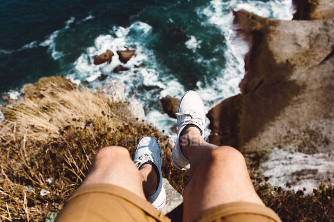 Looking down view of male standing on edge of coastal cliff — Stock Photo