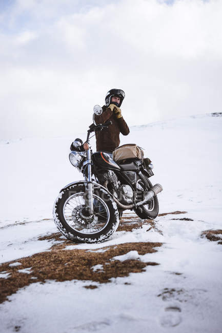 Mann trägt Motorradhelm im verschneiten Hochland — Stockfoto