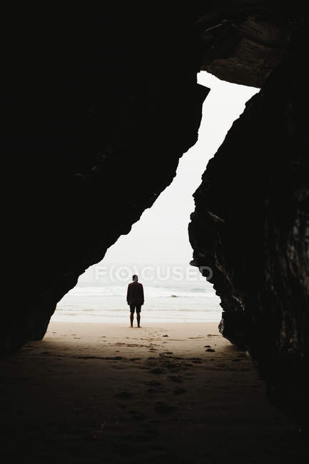 Silhouette of man standing at cliffs cove on background of foggy marine — Stock Photo