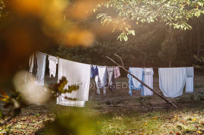 Patio trasero con ropa de cama colgada de las cuerdas y secado a la luz del sol de la mañana . - foto de stock