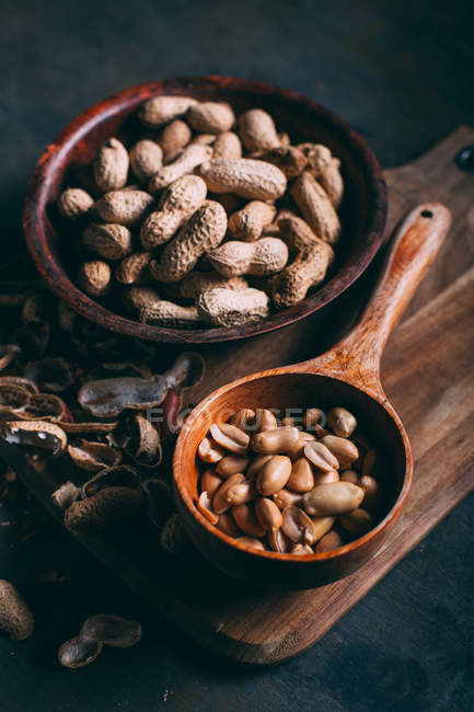 Ainda vida de amendoins em tigela de madeira e colher em tábua de corte — Fotografia de Stock