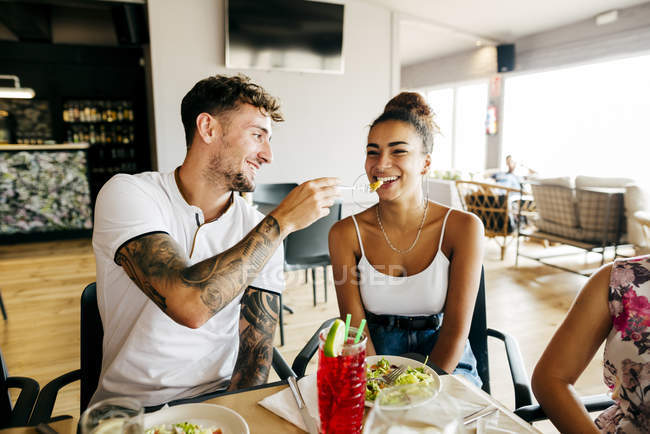 Smiling man feeding fries to smiling woman — Stock Photo