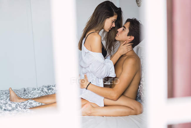 Paar auf Bett sitzend und sinnlich auf jeden einzelnen schauend — Stockfoto
