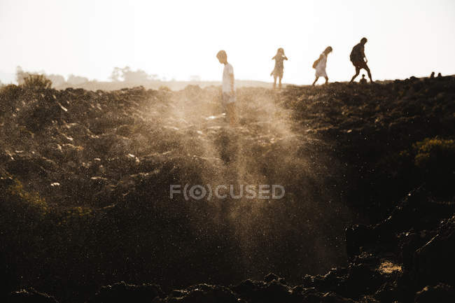 Silhouettes of people walking on cliff — Stock Photo