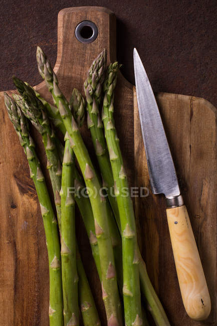 Top view of green asparagus with rural knife on wooden board — Stock Photo
