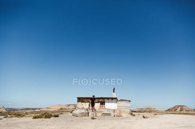 Человек в позе возле маленькой хижины в пустыне в солнечный день . — стоковое фото