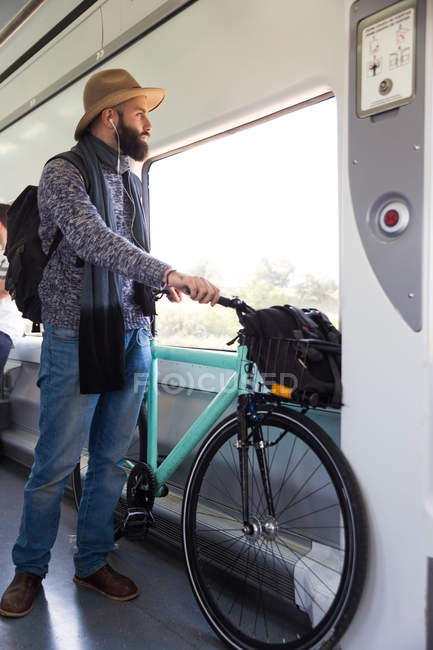 Бородатий чоловік їде в поїзді з велосипедом і слухає музику — стокове фото
