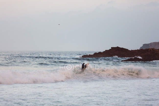 Surfer ridding on top of roiling wave at coastal shoreline — Stock Photo