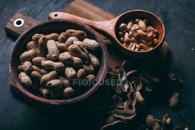 Close up view of shelled peanuts in wooden bowls cutting board — Stock Photo