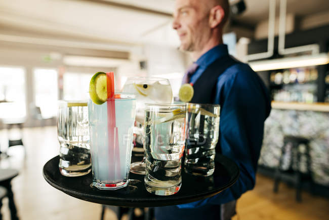 Close up view of drinks on tray carried by waiter — Stock Photo