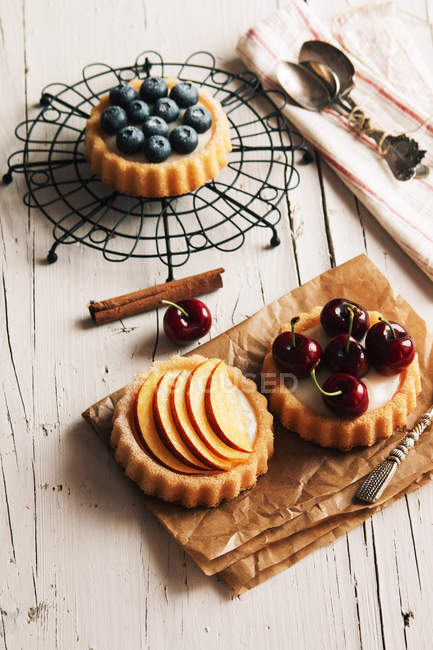 Bodegón de tartaletas rellenas de crema y fruta en tabletas - foto de stock