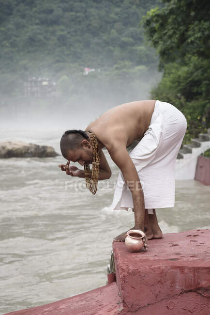 Side view of man putting dot on forehead at river. — Stock Photo