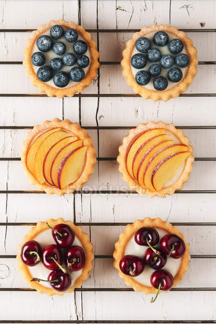 Arrangement of tartlets filled with cream and cherries seen from above — Stock Photo