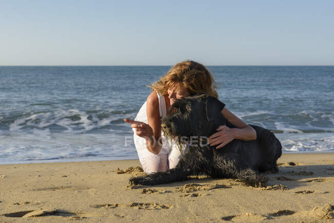 Erwachsene Frau mit Hund am Strand — Stockfoto