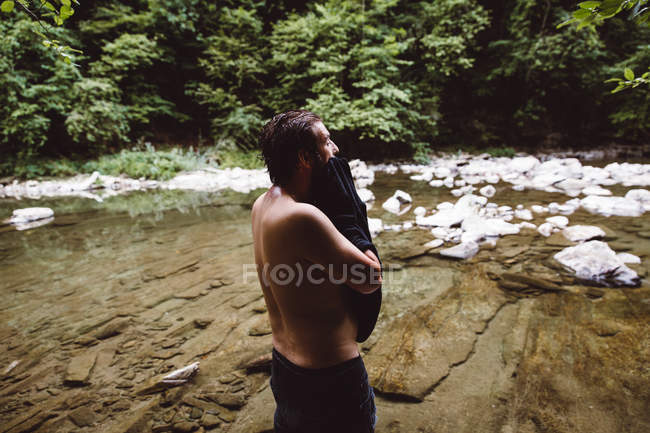 Вид збоку чоловік витирає рушником на річці в лісі . — стокове фото