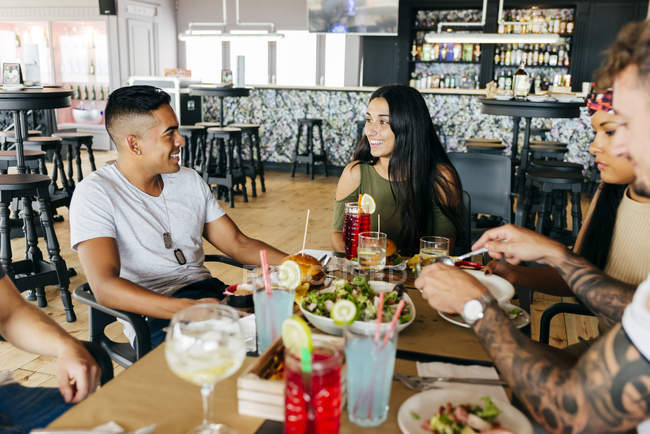 Grupo de amigos alegres jantando juntos no café — Fotografia de Stock