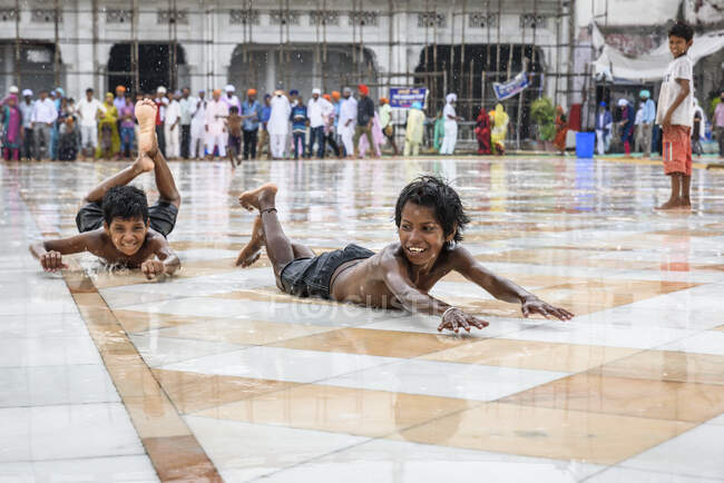 Lächelnde indische Kinder haben Spaß und spielen auf nassem Pflaster. — Stockfoto