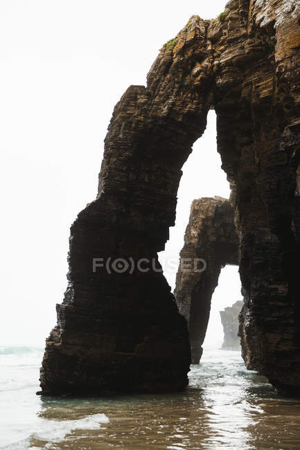 Paisagem de arcos rochosos na costa arenosa — Fotografia de Stock
