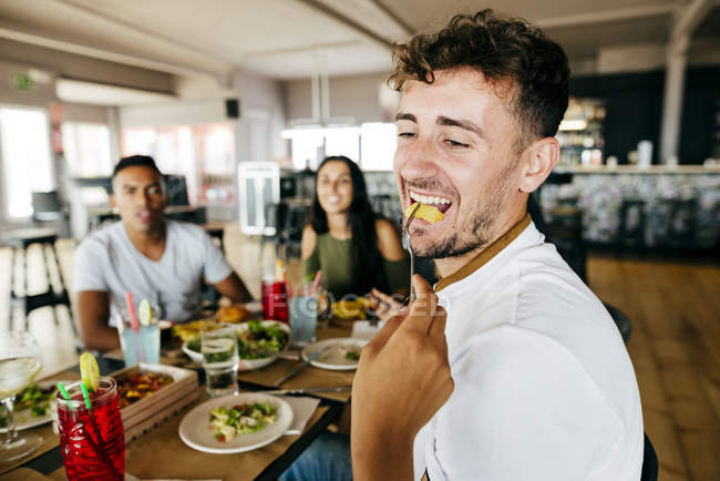 Crop hand of giving French fries to man while eating with friends at cafe — Stock Photo