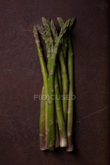 Fresh green asparagus on dark metal surface — Stock Photo