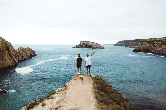 Fröhliche Männer stehen zusammen auf Klippe am Meer. — Stockfoto