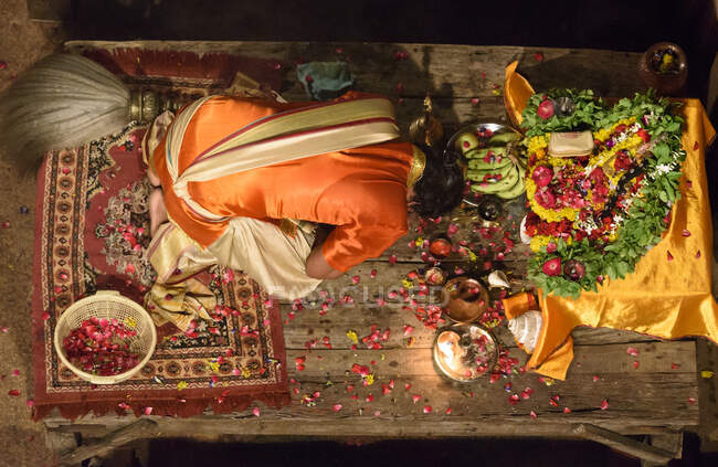 Сверху буддийский монах сидит за подарками на столе и поклоняется. — стоковое фото