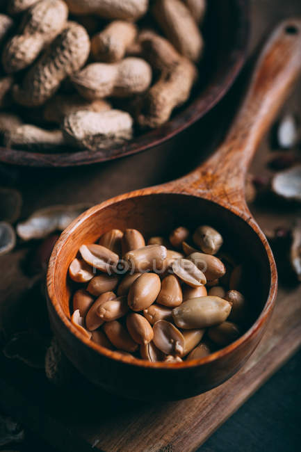 Close up view of fresh peanuts in wooden scoop on board — Stock Photo
