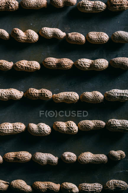 Padrão de amendoins com casca na superfície escura — Fotografia de Stock