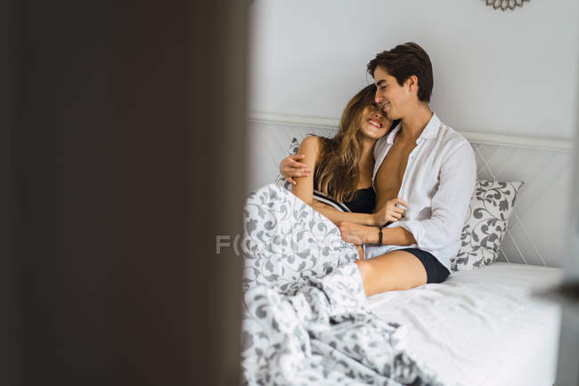 Portrait of young couple embracing at bed — Stock Photo