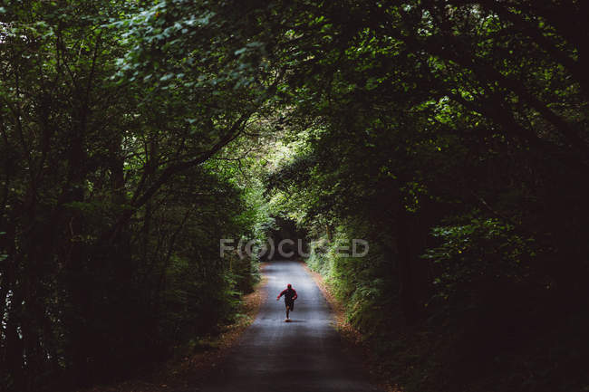 Uomo su skateboard su strada forestale — Foto stock
