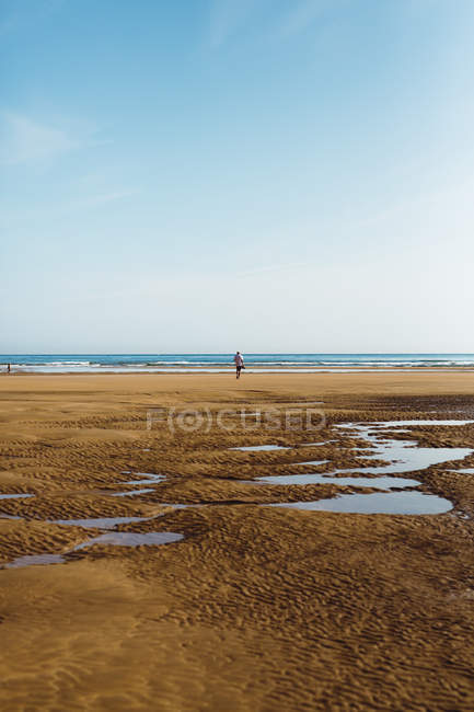 Unbekannter Mann läuft mit Paddeln auf nassem Sand am Strand — Stockfoto