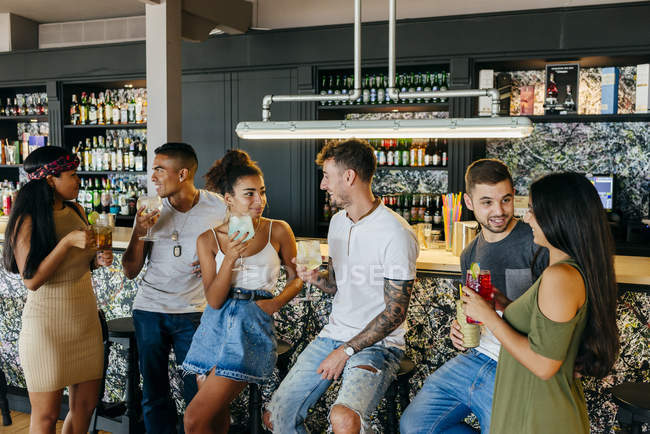 Друзья, стоящие у стойки бара и пьющие коктейли — стоковое фото