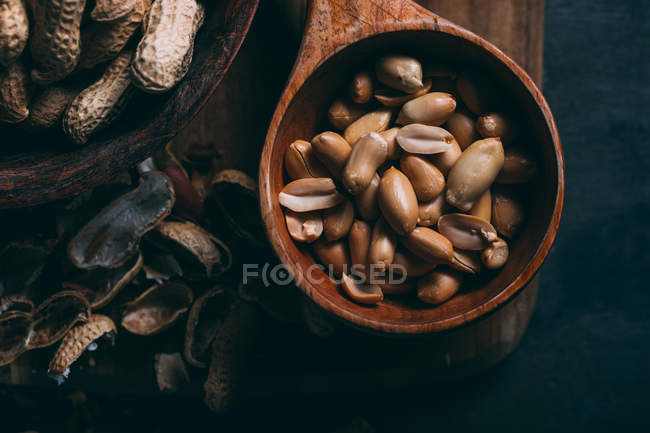 Close up view of peanuts in wooden scoop on board — Stock Photo