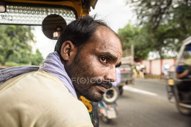 Adult local Indian man riding in rickshaw on road in town. — Stock Photo