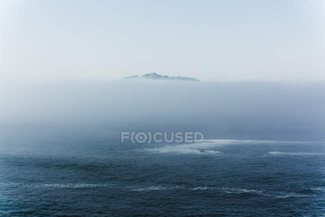 Luftaufnahme des Meeres mit Nebelwolke über einem Hügel im Hintergrund — Stockfoto
