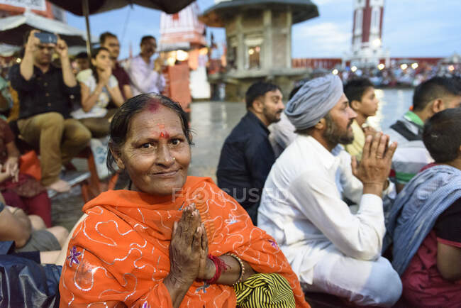 Adult Indian woman in traditional clothes looking at camera while praying in crowd. — Stock Photo